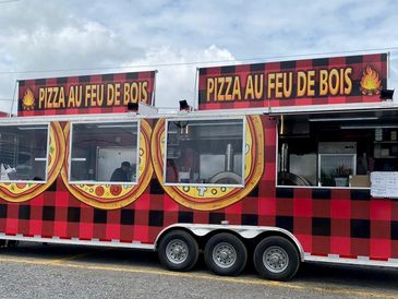 Red and black pizza food truck with wood-fired oven signs.