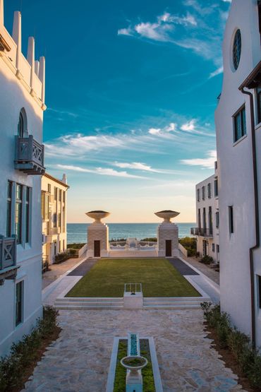 Elegant seaside courtyard with manicured lawn and ocean view at sunset.