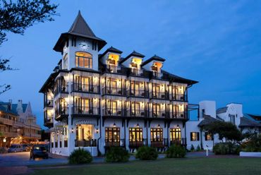 Charming multi-story building with warm lights at dusk and a clock tower.