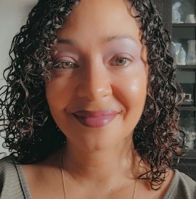 Close-up portrait of Tara Grenier with curly hair and a warm smile.