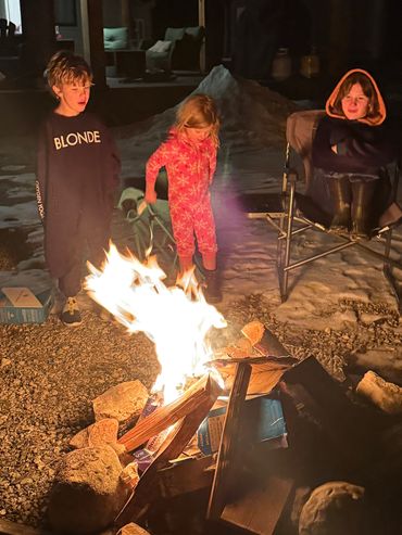 Guests gathered around a campfire at night.
