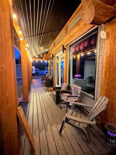 Evening view of a cozy wooden porch with string lights.
