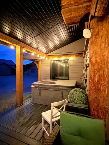 Cozy evening porch with hot tub and string lights.
