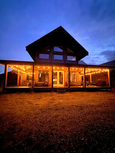 A warmly lit cabin at dusk with string lights.