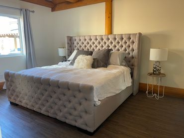 Bedroom with a tufted upholstered headboard and soft neutral bedding.