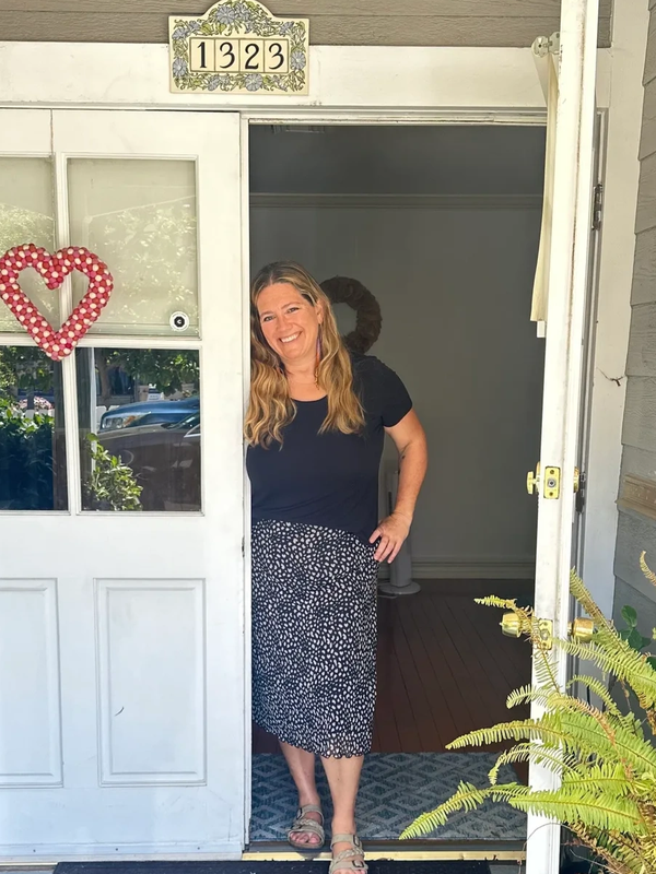 Smiling woman standing at the doorway of a house.