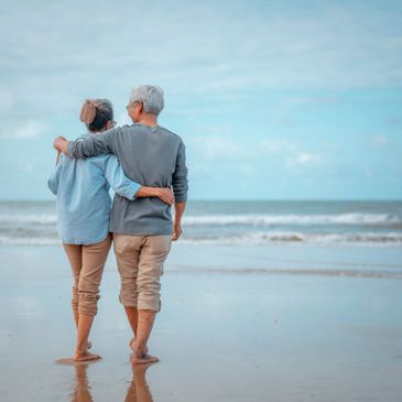 older couple walk together on a sunny beach