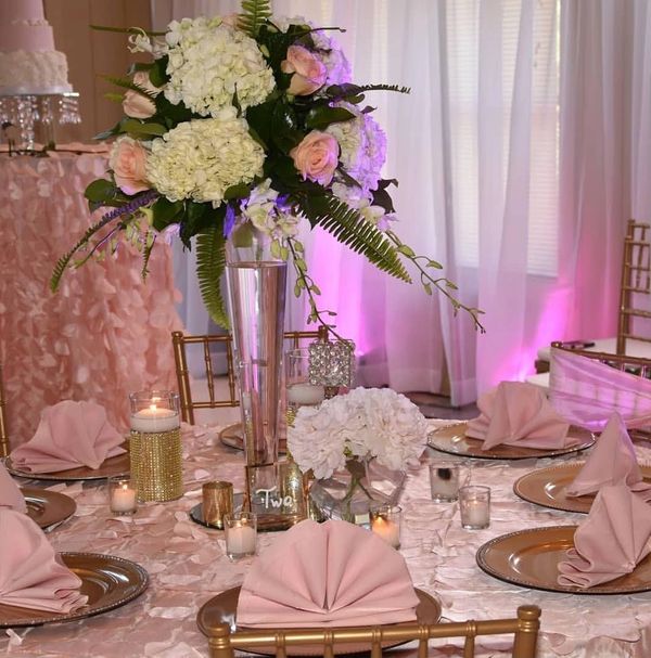 Elegant wedding table setup with pink and white floral centerpiece and gold accents.