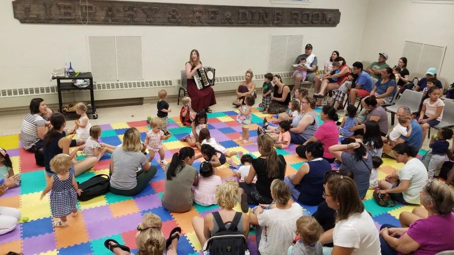Chloe performs accordion for a large group of children and parents,