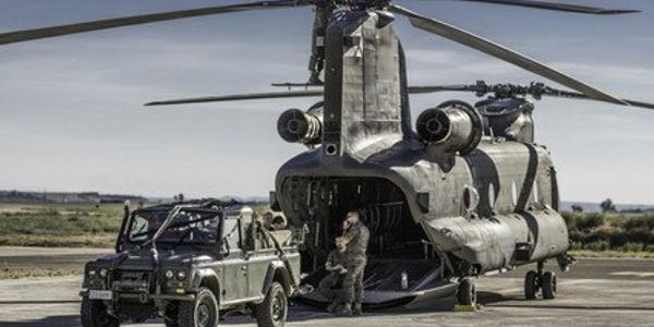 Military helicopter with soldiers and a jeep on a runway.
