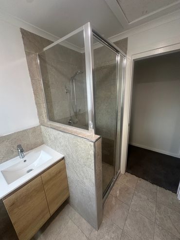 Modern bathroom with glass shower and wooden vanity.