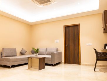Minimalist living room with beige walls, a gray sofa, and a wooden door.