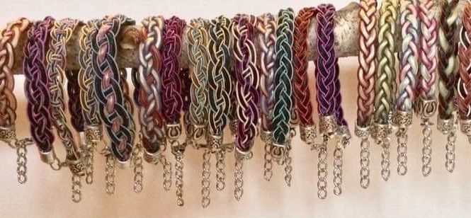 Colorful braided bracelets with chains on a rod.