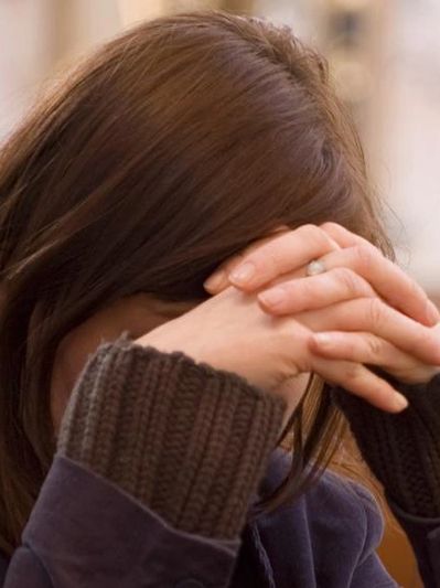 Girl with hands clasped against forehead in prayer.