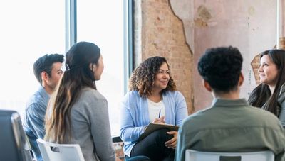 5 personas (3 mujeres, 12 hombres) en una discusión grupal.