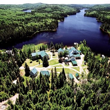A lakeside cabin retreat surrounded by dense forest and winding water.