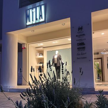Night view of a fashion store entrance with lavender plants in the foreground.