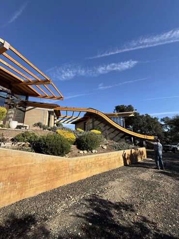 Modern house with wooden framework under a clear blue sky.