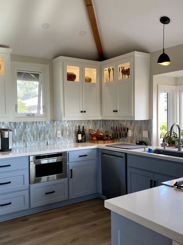 Modern kitchen with blue lower cabinets and white upper cabinets featuring glass display sections.