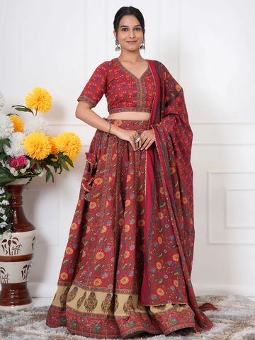 Woman in a red floral ethnic lehenga with dupatta, posing indoors.