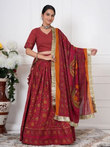 Woman in elegant red traditional Indian attire with gold accents.