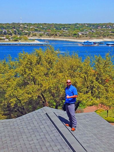 Home inspector on the roof with a lake in the background.