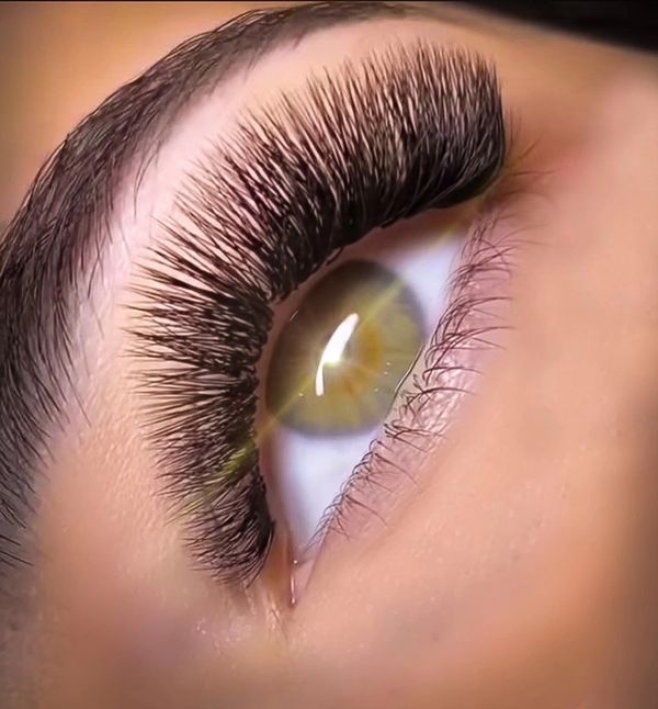 Close-up of an eye with long, thick eyelashes and a greenish-brown iris.