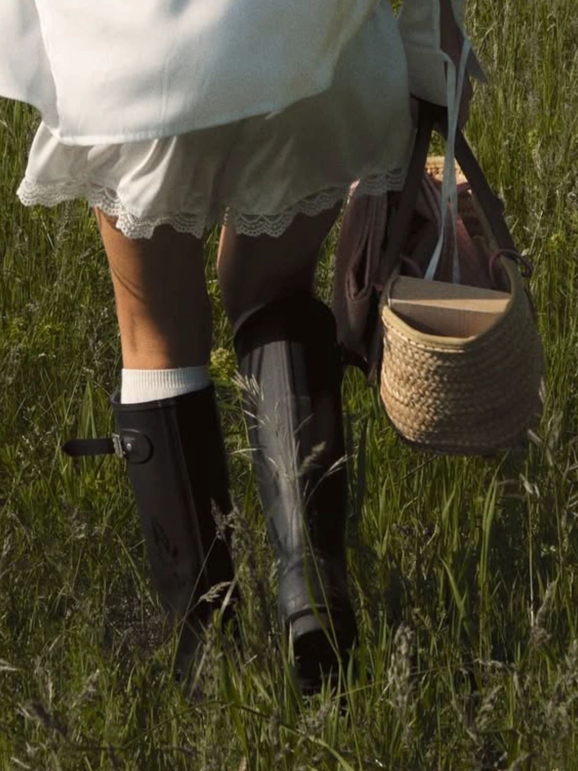 Farm lifestyle in Jupiter Farms — woman walking through grass with woven basket, natural elegance
