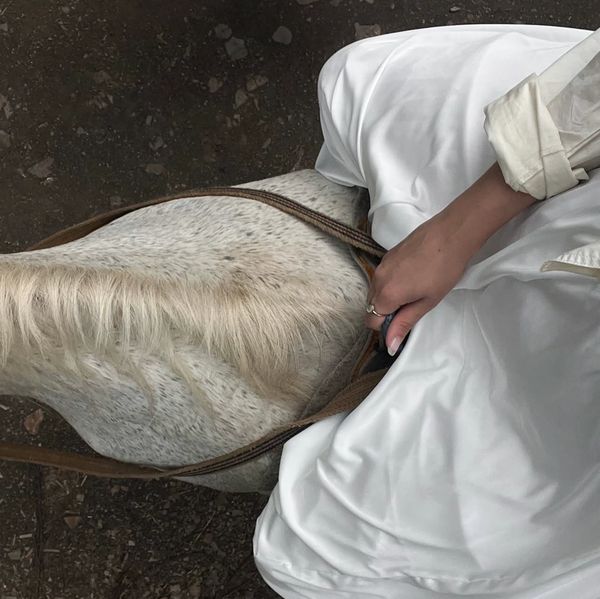 Rustic farm lifestyle — woman in white dress gently holding horse reins — Jupiter Farms FL