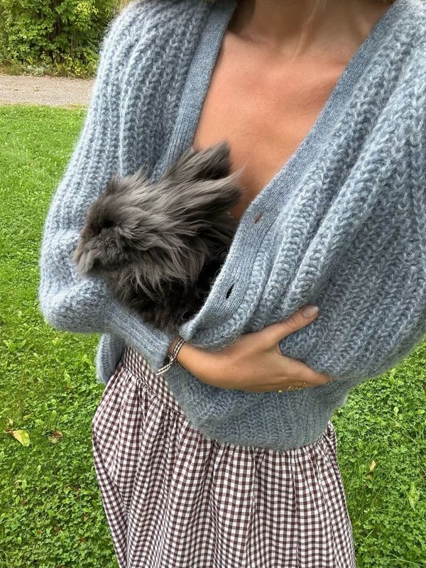 Farm lifestyle — woman in knit sweater holding fluffy bunny outdoors — Jupiter Farms Florida