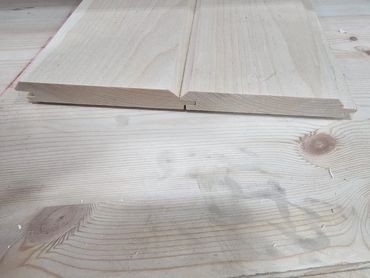 Two interlocking wooden planks with tongue and groove edges on a wooden surface.