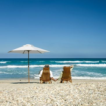 A retired couple holding hands on a beach