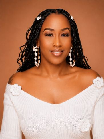 Smiling woman with braided hair and shell earrings in white sweater.