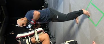 Two men practicing boxing with gloves and pads in a gym.