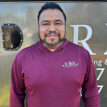 Man in maroon hoodie with RBR Landscaping logo smiling.