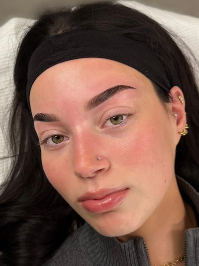 Close-up of a woman with clear skin and well-groomed eyebrows.