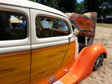 Classic car with wood paneling and orange fenders at a car show.