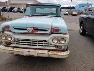 Rusty vintage Ford pickup truck with faded blue paint.