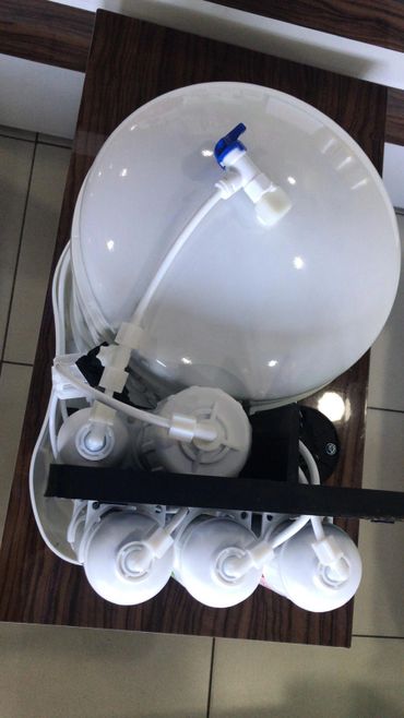 A water filtration system with multiple white filter cartridges and tubing.