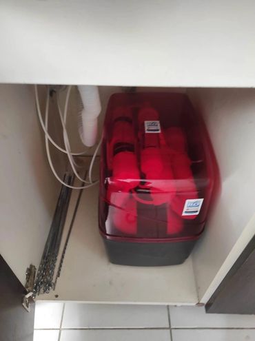 Red water filter system installed under a kitchen sink cabinet.