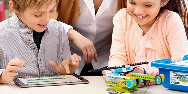 Niños jugando con un robot y una tablet.