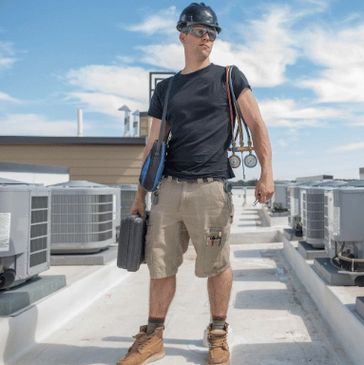 A MAN STAND ON A LOT OF HVAC WITH EQUMENTS BAG AND ENSTRUMENT ON ROOF OF A BULDING