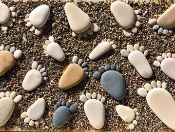 Various footprints made of stones arranged on a sandy surface.