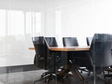 Modern conference room with black office chairs around a wooden table.