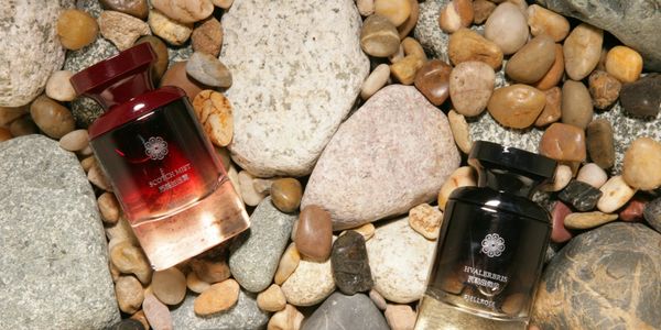 Two perfume bottles on a bed of assorted pebbles and stones.