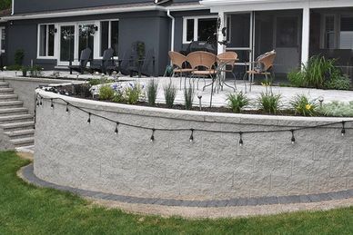 Stone patio with outdoor seating and string lights on retaining wall.