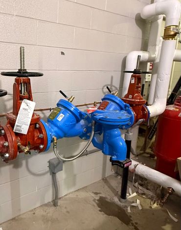 Industrial valves and pipes with blue and red components in a utility room.