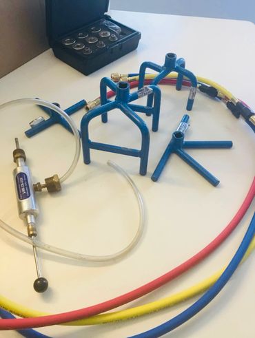 Set of blue valve spring compressors with hoses and accessories on a white surface.