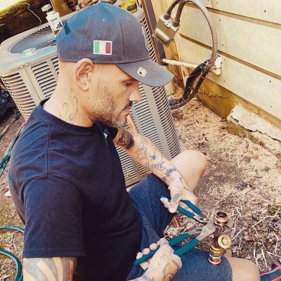 Man fixing outdoor air conditioning unit with tools.