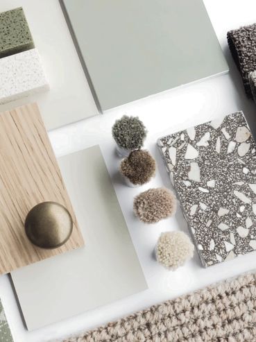 Interior design material samples including wood, fabric, and stone in neutral and green tones.